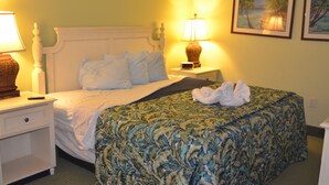 A neatly made bed with a floral bedspread, two bedside lamps, and a framed picture on the wall.