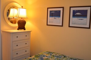 Um quarto com penteadeira branca, uma luminária e duas fotos emolduradas na parede.
