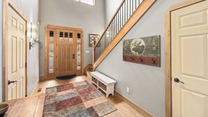 A hallway with a wooden bench, a rug, and a welcome sign.