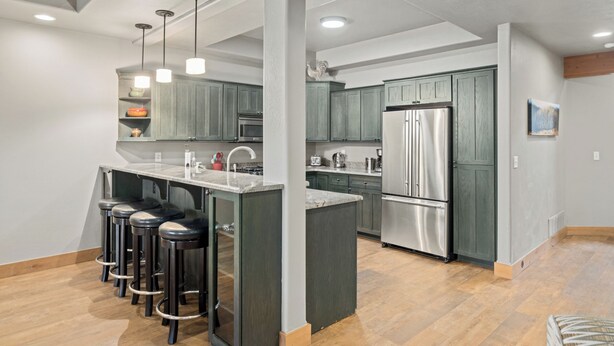 A modern kitchen with bar stools, a refrigerator, and a sink.