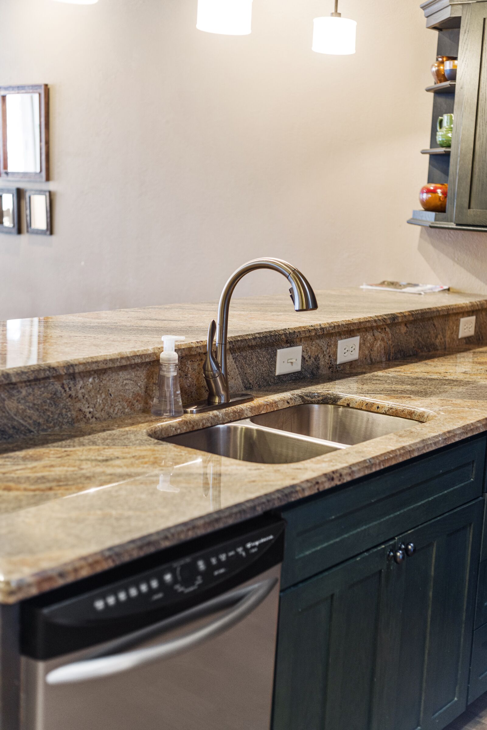 A kitchen with granite countertops, stainless steel sinks, and a dishwasher.