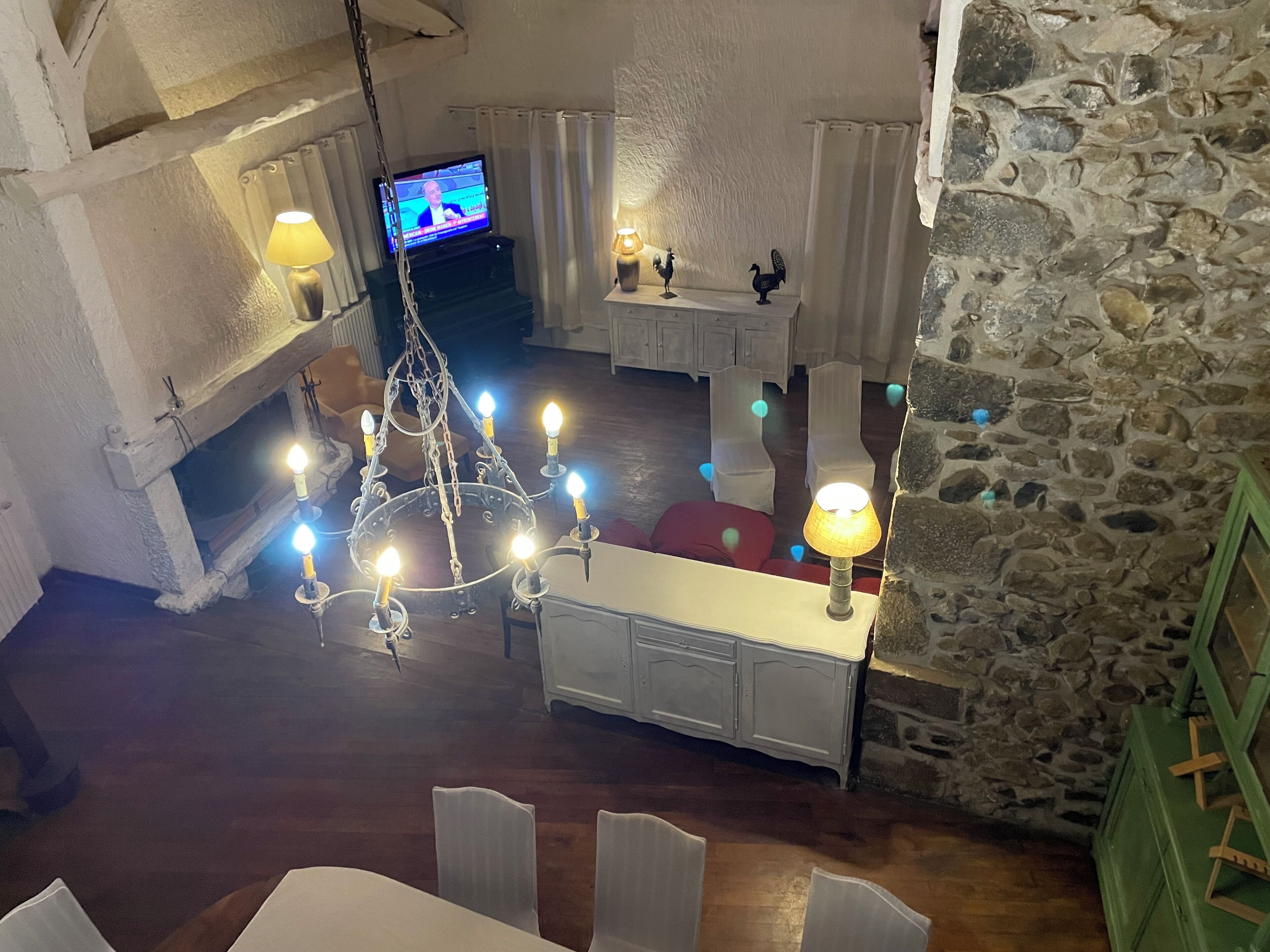 Une pièce chaleureuse avec un lustre, un téléviseur et un mur en pierre.