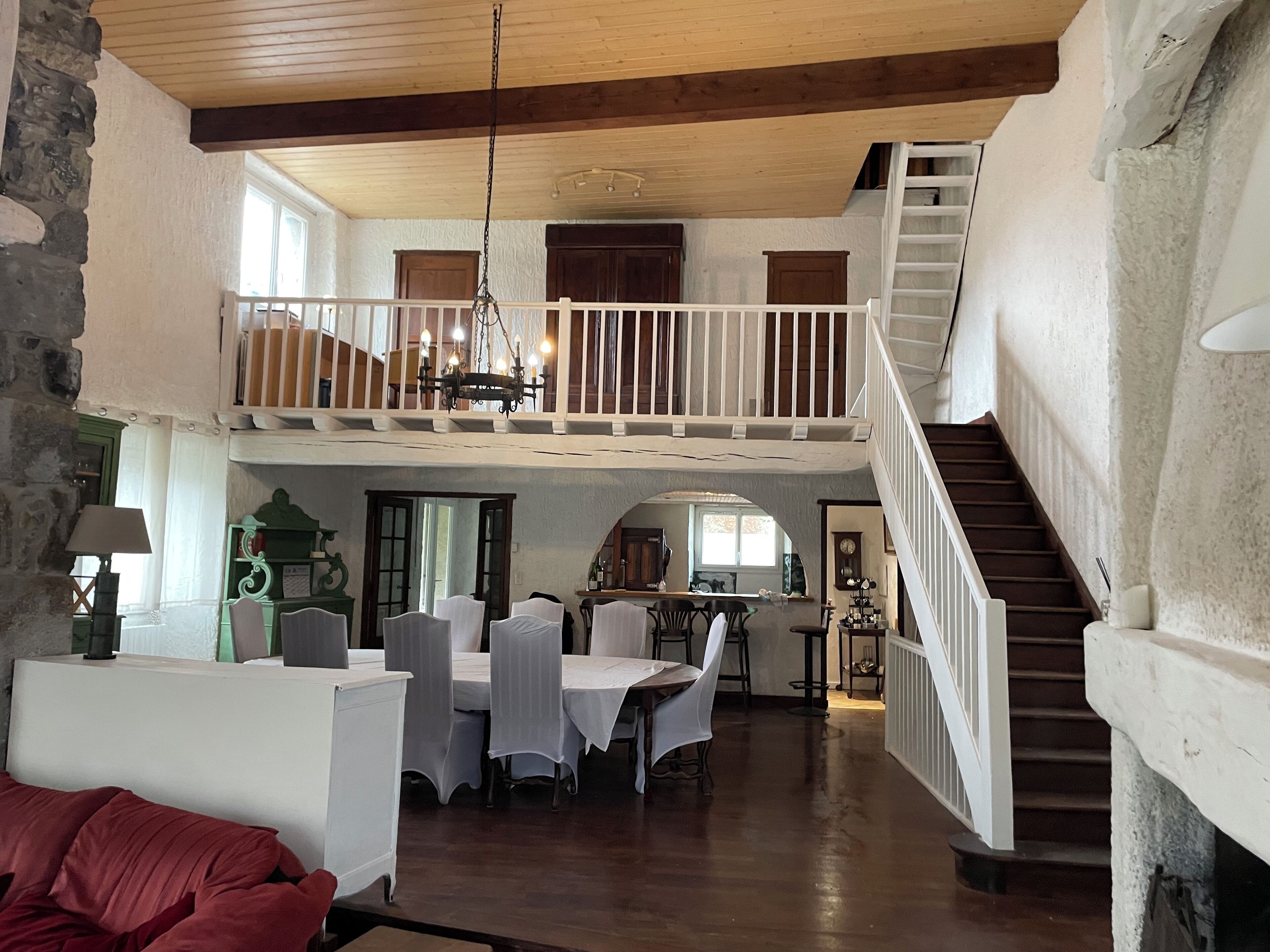 Ein großzügiger Loft mit hohen Decken, einer Treppe und einem Essbereich mit Tischen und Stühlen mit weißen Tischdecken.