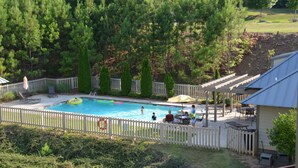 Un patio trasero con piscina, rodeado por una valla de madera y un área de patio con mobiliario exterior.