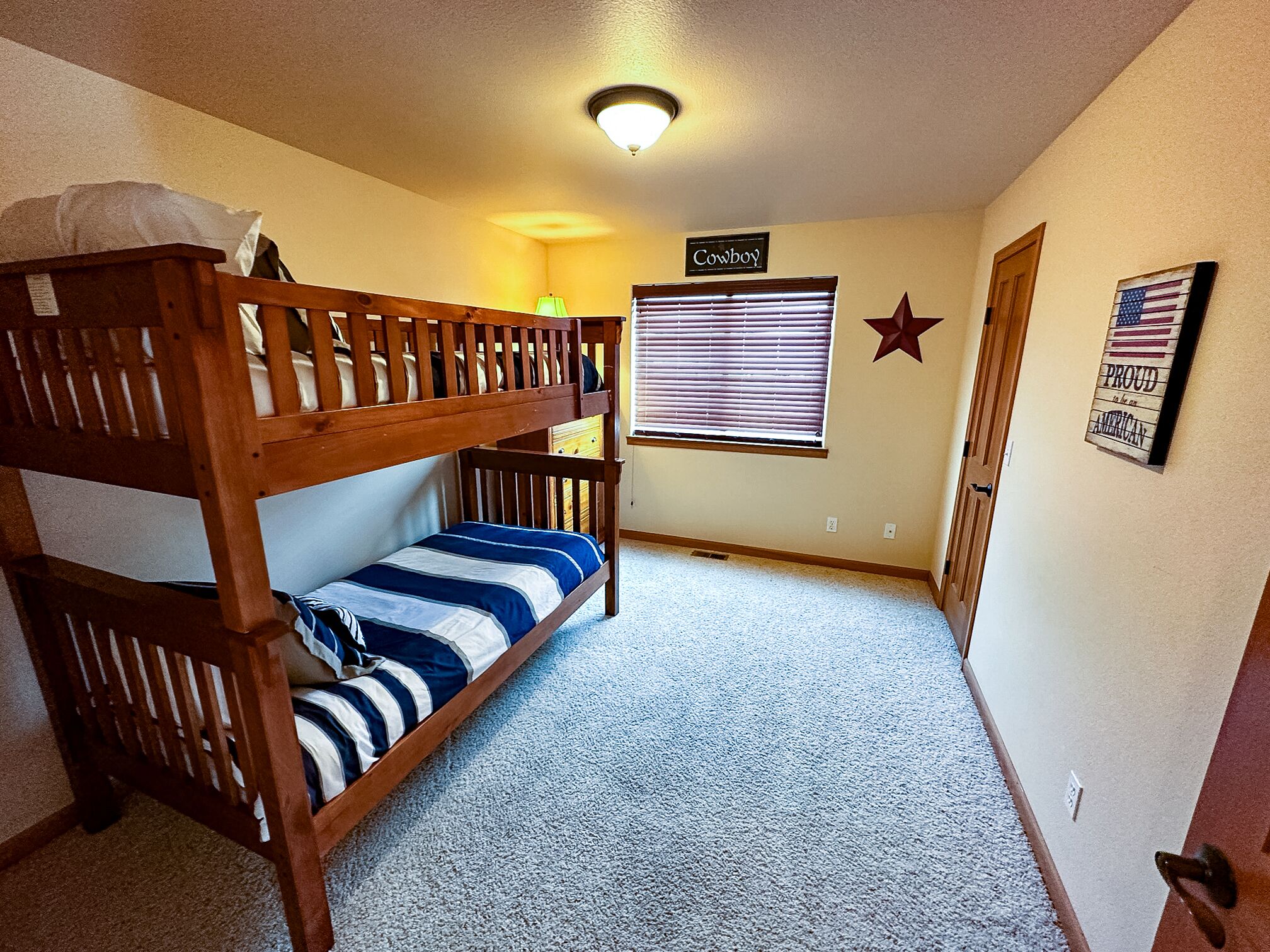 A bunk bed room with a window, a star decoration, and a sign that says "Cowboy".