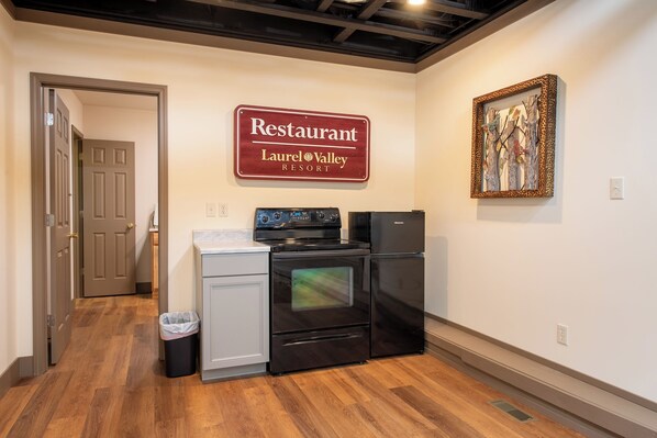 Een keuken met een fornuis, oven en een koelkast, een afvalbak en een bord met Restaurant Laurel Valley Resort.