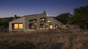Uma casa moderna com fachada de pedra, grandes janelas e interior bem iluminado.