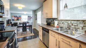 Cocina moderna con lavavajillas, estufa y un lavabo amplio. Hay un comedor con mesa y sillas.