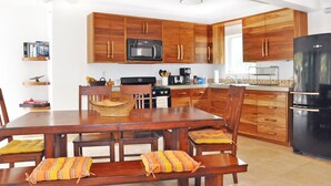 Une cuisine moderne avec des meubles en bois, un réfrigérateur noir et une table à manger avec des chaises rembourrées.