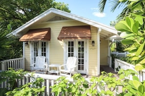 A house with a porch, two white chairs, and a number '717' on the wall.