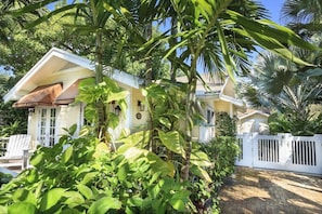 A house with a white exterior, a brown roof, and a white fence.