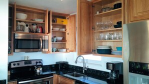 Eine Küche mit Holzausstattung, einer Mikrowelle, einem Backofen, einer Kaffeemaschine und einem Spülbecken.