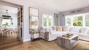 A spacious living room with a white sofa, a coffee table, and a dining area with a table and chairs.