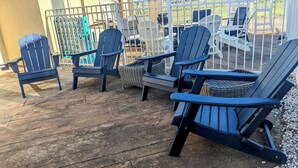Une terrasse dotée de plusieurs chaises Adirondack et de meubles en osier.
