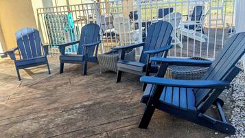 Um deck com várias cadeiras Adirondack e móveis de vime.