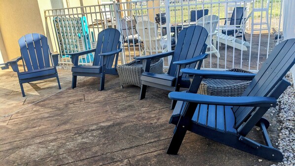 A deck with several Adirondack chairs and wicker furniture.