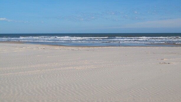 Une plage avec des dunes de sable et l’océan.