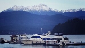 A marina with several boats docked, a small building, and a mountain range in the background.