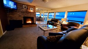 A cozy living room with a fireplace, leather furniture, and a view of the ocean.