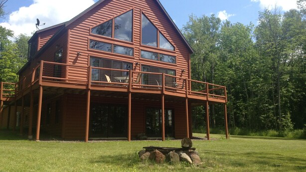 A two-story log cabin with a balcony and large windows.