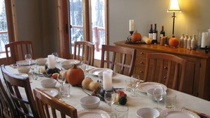 A dining table set for a meal with white plates, clear glasses, and candles.
