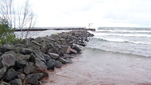 A rocky shoreline with waves crashing against a pier.