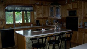 A kitchen with a central island, bar stools, wooden cabinets, a dishwasher, and a refrigerator.