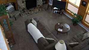 A cozy living room with a stone fireplace, a flat-screen TV, a comfortable sofa, and a coffee table.