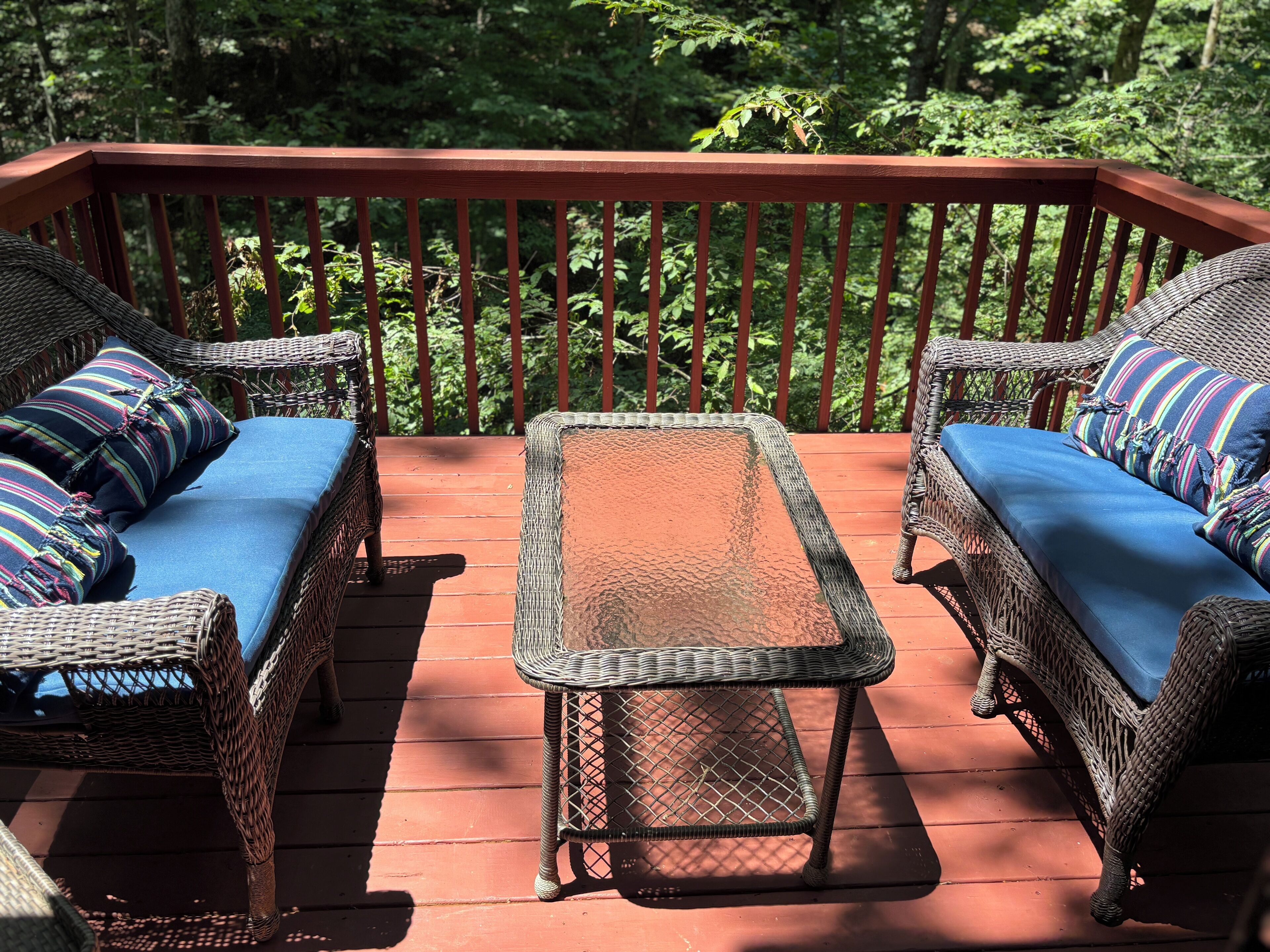 A wooden deck with wicker furniture and a metal table.
