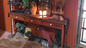 Une console en bois agrémentée d’objets décoratifs, d’un miroir et d’appliques murales, le tout placé devant un mur orange.