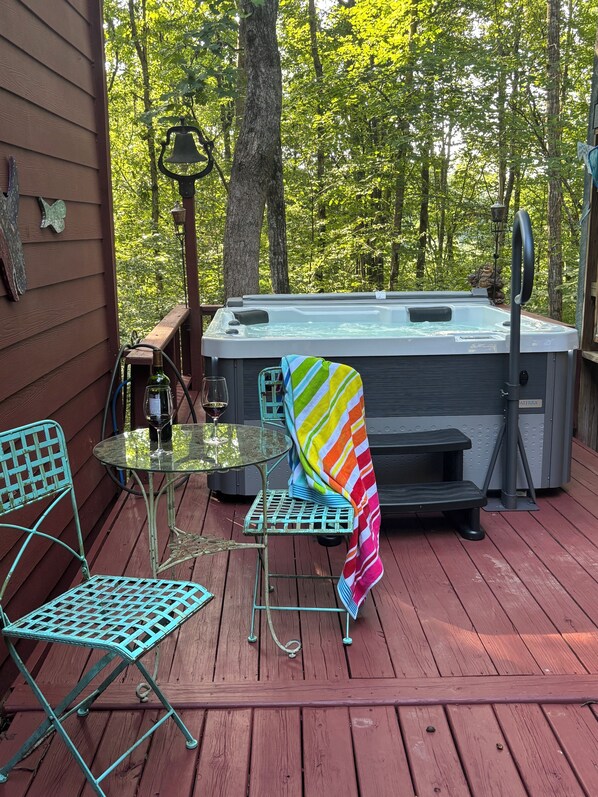 A wooden deck with a hot tub, a glass table, and metal chairs. - River House with Pizzazz on the Upper Chattahoochee River (Demorest)