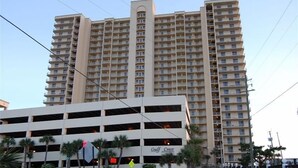 Un hotel de gran altura con varios pisos, un hueco central para ascensores y un garaje de estacionamiento al frente.
