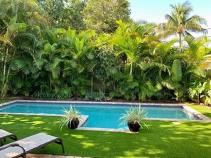 Une piscine entourée d’une végétation luxuriante et de palmiers.