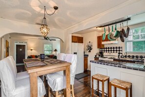 Une cuisine moderne dotée d’un îlot central, de luminaires suspendus et de casseroles accrochées.