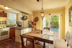 Une cuisine avec un coin repas, un luminaire suspendu et une vue sur une piscine.