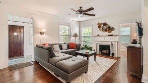 A living room with a sectional sofa, a fireplace, and a ceiling fan.