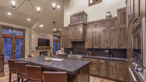 Una cocina amplia con una isla grande, armarios de madera, una chimenea de piedra y electrodomésticos modernos.
