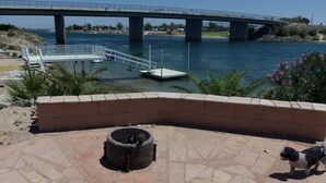 A paved area with a brick wall, a small fire pit, and a dog. - WATERFRONT,PRIVATE BOAT RAMP ,SANDY BEACH GATED COMMUNITY, 3 BEDROOM & 2 BATH (Mohave Valley)