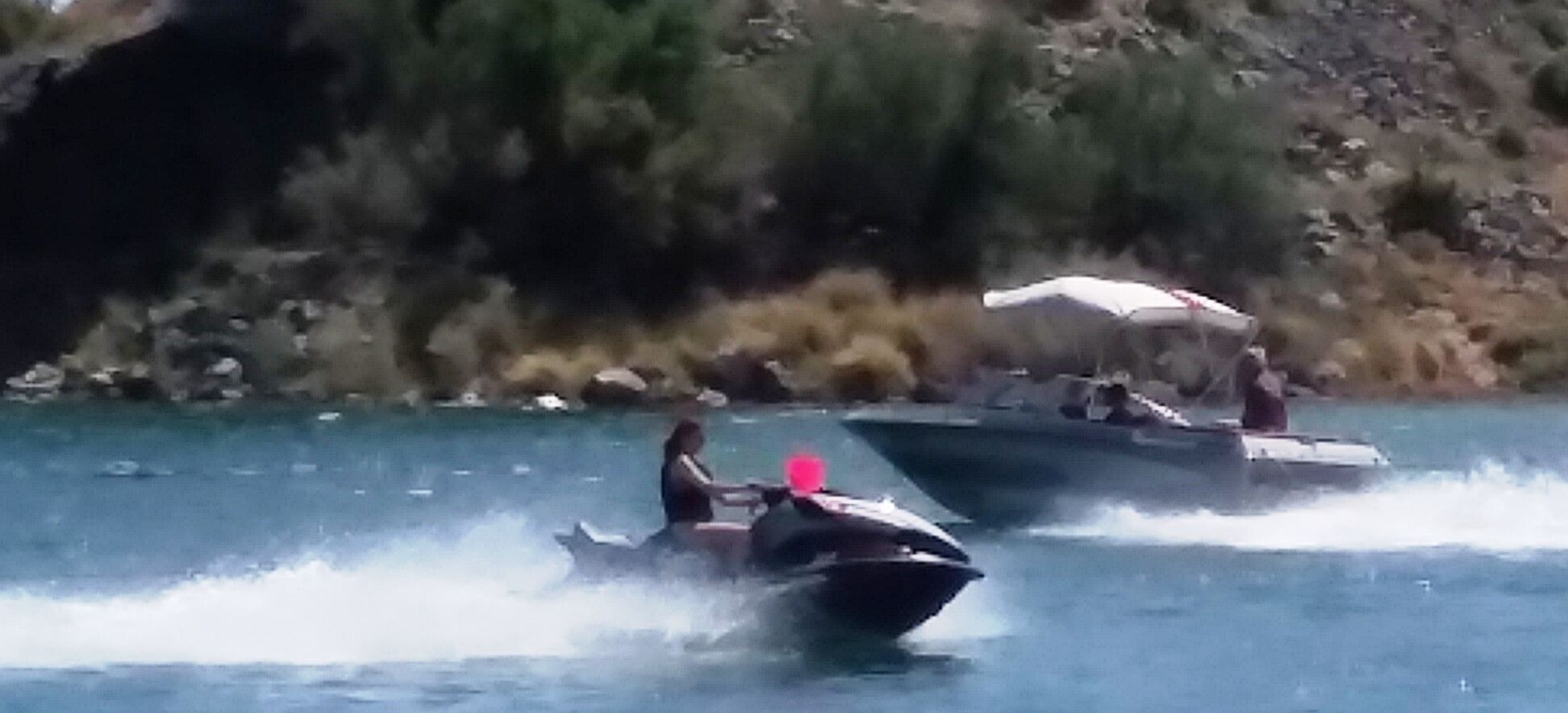 A boat with two people on it, moving on water.