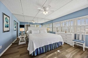 Un dormitorio con cama, una silla, un escritorio, un espejo y una ventana con persianas.
