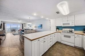 A modern kitchen with white cabinetry, a large island, a microwave, and a stove.