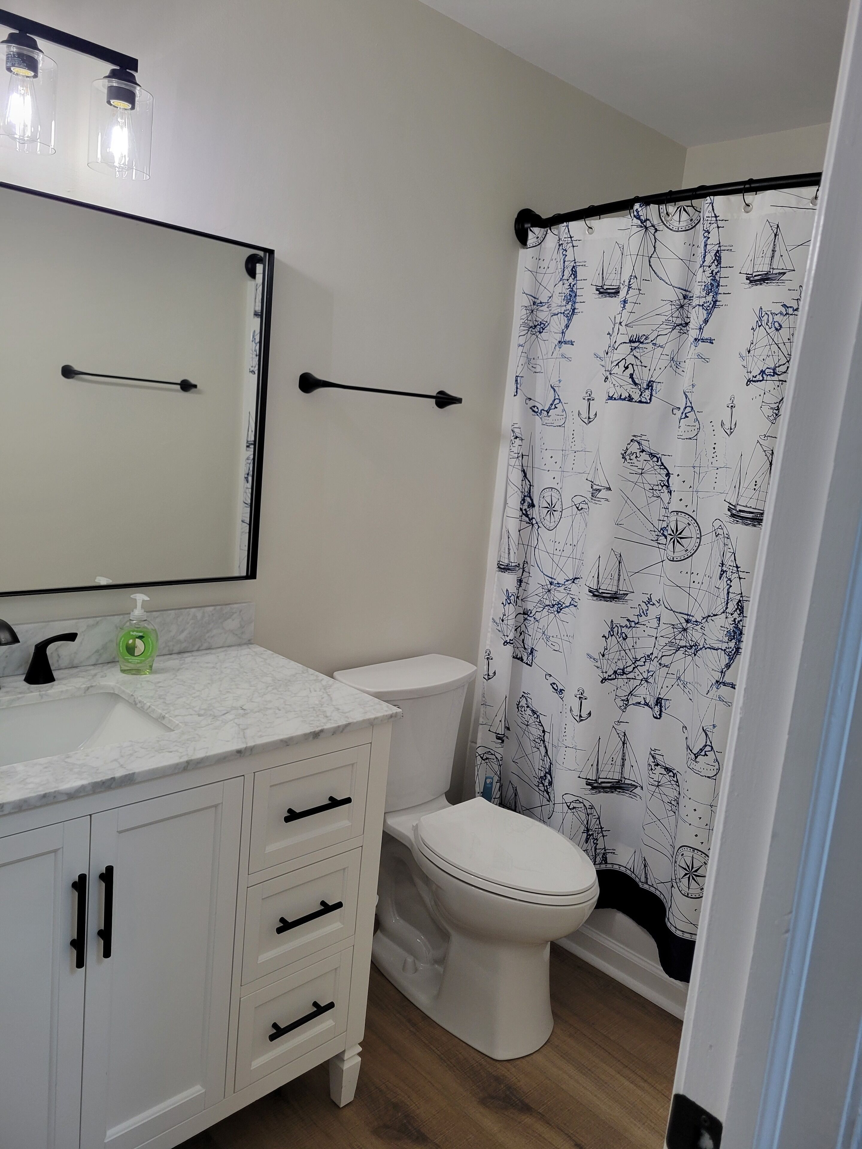 A bathroom with a white toilet, a white sink with a marble countertop, and a mirror above the sink.