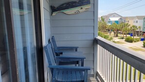 A balcony with two blue chairs and a decorative fish wall hanging. - Surfside Beach Paradise! Steps to the Beach, Ocean View, Family Friendly (Surfside Beach)