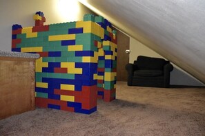A room with a carpeted floor, a wooden desk, and a colorful block structure.
