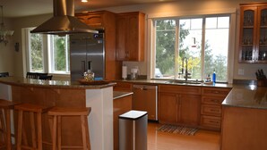 Una cocina moderna con armarios de madera, electrodomésticos de acero inoxidable y un amplio ventanal que proporciona luz natural.