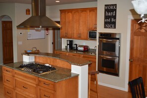Una cocina con armarios de madera, una campana extractora de acero inoxidable, un microondas y un horno.