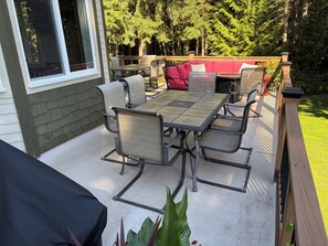 Eine Terrasse im Freien mit Tisch und Stühlen, umgeben von einer Holzterrasse und einer Backsteinmauer.