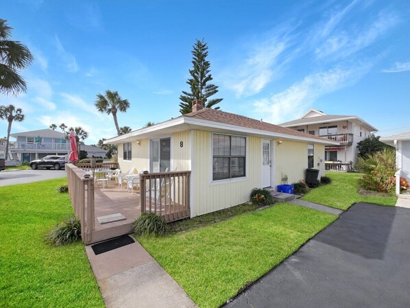 A single-story mobile home with a front porch, a small deck, and a well-maintained lawn.
