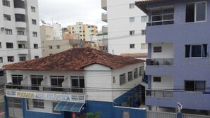 Un edificio con fachada azul y blanca, techo de tejas rojas y entrada protegida por una verja.