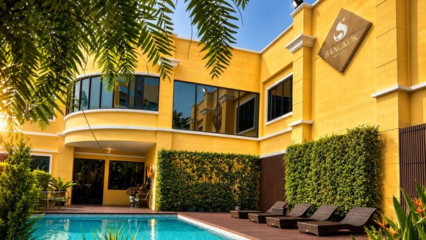 Un hotel moderno con piscina, area salotto esterna e giardino curato.